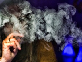 A woman takes a puff from a cannabis vape pen.