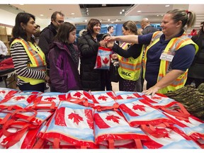 Then-newly-arrived Syrian refugee Anjilik Jaghlassian, centre, and her family receive winter clothes and other items at Pearson International airport, in Toronto on Dec. 11, 2015.
