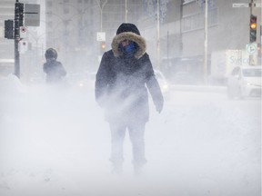 A woman is hit by a blast of blowing snow as she heads west on Blvd. Rene-Levesque in downtown Montreal.