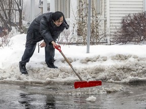 Zuan Zhu tries to clear water and ice from a drain in Lachine in January.