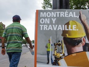 A Latin American migrant worker who labours on a Quebec farm walks past a sign reading "We work on Montreal" in Montreal in 2015.