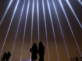 A couple stands in silhouette against some of the 14 beams of light pointing skywards at the Mont Royal Chalet in commemoration of the 14 victims murdered at Polytechnique on Dec. 6, 1989.