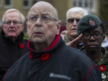 Master Corporal Lynsaskia Clement salutes as George Flahiff (foreground) and others sing O Canada during  the Remembrance Day ceremony in Montreal on Sunday, Nov. 10, 2019.