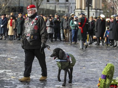 A veteran walks with his service dog after laying a wreath during Remembrance Day ceremony at Place du Canada in Montreal on Monday, Nov. 11, 2019.