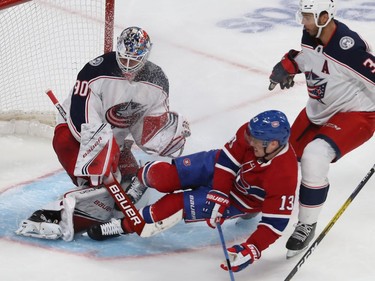 Montreal Canadiens Max Domi (13) slides into Columbus Blue Jackets goaltender Elvis Merzlikins with Seth Jones (3) coming in on play, during third period NHL action in Montreal on Tuesday November 12, 2019.
