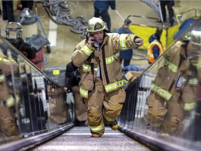 Montreal fire service division chief Michel Bourgeois speaks on the phone while climbing the escalator in the flooded Square-Victoria–OACI métro station Thursday.