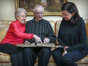 Howard McNamara looks through a scrapbook with his wife Anne and daughter Judi at his home in St-Laurent. He turns 100 in January.
