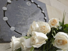 Fourteen white roses sit at the base of a memorial plaque at École Polytechnique in  Montreal in this Dec. 6, 2013 file photo.