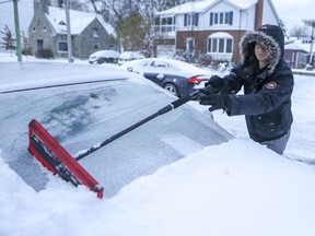 Vitali Obraztsov clears snow from his car in the the Lachine borough on Tuesday.
