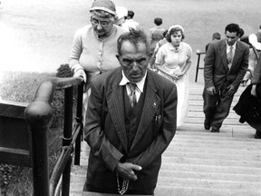 In this 1955 photo, a man holding rosary beads kneels on a step leading to St. Joseph's Oratory in Montreal while others make their way up the stairs.