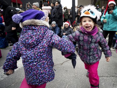 Kimberly Hubert, 6, left, and Daphnee Perron Demattos, 5, dance to Christmas songs as they wait for Santa during the annual Santa Claus parade in Montreal on Saturday, Nov. 23, 2019.