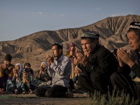 In this file photo, a Uighur family prays at the grave of a loved one at a local cemetery in western Xinjiang province, China. Up to one million Uighur are held in 're-education' camps in China.