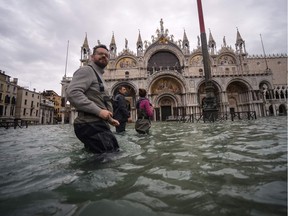 A general view shows people walking across the flooded St. Mark's Square, by St. Mark's Basilica on Friday, Nov. 15, 2019, in Venice, two days after the city suffered its highest tide in 50 years.