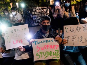 People hold placards and mobile phones as they gather to pray for the students who are barricaded inside Hong Kong Polytechnic University at Salisbury garden in Tsim Sha Tsui district of Hong Kong on Nov. 19, 2019.