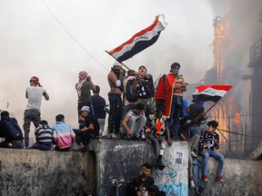 An Iraqi demonstrator carries the Iraqi flag during continuing anti-government protests in Baghdad on Saturday, Nov. 30, 2019.