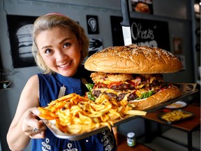 A woman holds up what the Chris Steaks & Burgers restaurant says is Thailand's biggest burger weighing more than 6 kilograms, before a competition held to eat it at the restaurant in Bangkok, Thailand, October 11, 2019. Picture taken October 11, 2019. REUTERS/Jiraporn Kuhakan     TPX IMAGES OF THE DAY