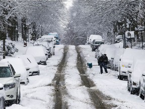 A man shovels snow before the snowplow has come on West Hill Ave. in the Notre-Dame-de-Grâce district of Montreal on Tuesday, Dec. 31, 2019.