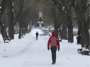 People walk along the sidewalk in Jeanne-Mance Park following the season's first snowstorm to hit Montreal, on Tuesday November 12, 2019.