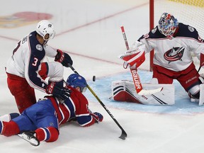 Canadiens' Max Domi slides toward Columbus Blue Jackets goaltender Elvis Merzlikins after being brought down by Columbus Blue Jackets' Seth Jones during second period  in Montreal on Nov. 12, 2019.