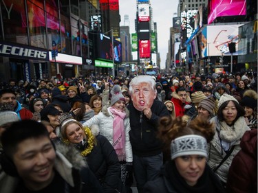 A man wears a mask of U.S. President Donald Trump as people wait to celebrate New Years Eve in Times Square on December 31, 2019 in New York City. Because of the mild weather, a larger than usual crowd of people visiting from all over the world is expected to watch the ball drop.