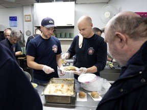 Montreal firefighters Joe Messier, left, and Thierry Martin serve clients lunch at St. Michael's Mission in Montreal on Thursday, Dec. 5, 2019.
