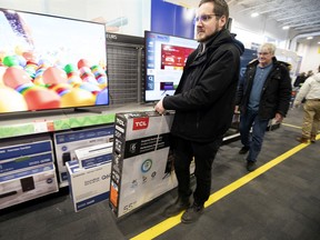 Kyle Cross and his father, Alan Cross, purchase a 55-inch TV that was reduced by $200 during the Boxing Day sale at the LaSalle Best Buy store on Thursday.