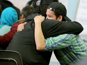 A young man gets a hug from a friend during talk of recent events. In the wake an epidemic of suicide attempts in Attawapiskat - including 11 young people last Saturday and a foiled suicide pact earlier this week - this remote Ontario reserve of 2,000 people declared a state of emergency over the weekend.  Today (April 13, 2016), Ontario's Minister of Health, Eric Hoskins, arrived on the reserve, along with Tracy MacCharles (Minister of Children and Youth) and Chief of the Assembly of First Nations, Perry Bellegarde, to hatch out solutions. They include an immediate two million dollars in emergency funding, plans to build a youth centre and other long-term strategies.  (JULIE OLIVER/POSTMEDIA) ORG XMIT: POS1604131656562849