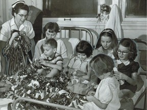 Original caption: "All of these children will be well enough to go home for Christmas, even if just for the day. Here Nurse Margaret Goodenough helps them prepare Christmas decorations for the hospital's Tiny Tim party next Wednesday for those who have to stay." This photo, taken at the Montreal Children's Hospital, is dated Dec. 17, 1955.
