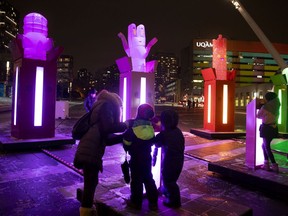 Kids activate pop up figures by creating noise with a microphone at the POP! by Gentilhomme light show at Place des Festivals in Montreal.