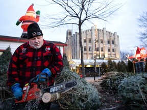 Christian Marois cuts the bases of Christmas trees as he prepares for the evening rush at Atwater Market in Montreal, on Monday, December 16, 2019. Marois says the market is busy every night from 4 to 6pm.
