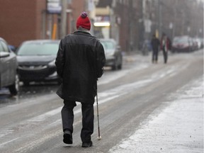 A visually impaired elderly man uses his white cane to follow the tire path on 5th Ave. in Verdun. The sidewalks were covered in ice Dec. 27, 2019.