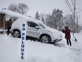 Rachel Langlois and her husband Yvon Calbert take a break from shovelling and clear their car in Pointe-Claire on Tuesday, Dec. 31, 2019.