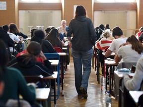 A teacher walks through a classroom as high school students take the philosophy exam, the first test session of the 2019 baccalaureate (high school graduation exam) on June 17, 2019 at the Pasteur high school in Strasbourg, eastern France. (Photo by FREDERICK FLORIN / AFP)FREDERICK FLORIN/AFP/Getty Images