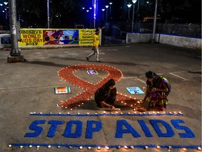 Volunteers light candles forming the shape of a red ribbon and a message reading 'Stop AIDS' during an awareness event on the occasion of the 'World AIDS Day' in Kolkata on December 1, 2019. (Photo by Dibyangshu SARKAR / AFP)