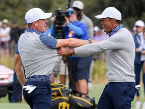 U.S. players Justin Thomas (L) and Tiger Woods (R) celebrate winning the match during the second day of the Presidents Cup golf tournament in Melbourne on December 13, 2019.