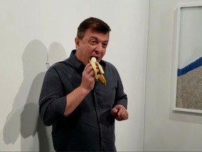 David Datuna eats a banana that was attached with duct tape to a wall, which was an artwork titled 'Comedian' by the artist Maurizio Cattelan, in front of a crowd at Art Basel in Miami Beach on December 7, 2019.(Ronn Torossian via REUTERS)