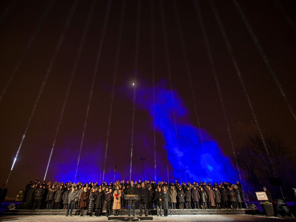  prime minister justin trudeau, centre, flanked by premier françois legault and mayor valérie plante, speaks during a vigil on mount royal marking the 30th anniversary of the mass shooting at École polytechnique.