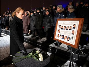 Canada's Governor General Julie Payette lays a white rose during a vigil on Friday, Dec. 6, 2019, on top of Mount Royal in front of a photo showing the 14 women who were killed in 1989. The ceremony marked the 30th anniversary of the mass shooting at École Polytechnique, in which 14 women who were killed and 14 were injured.