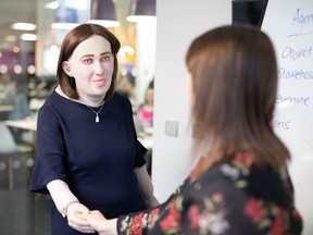 Emma shakes the hand of an office colleague. With grisly skin, bloodshot eyes, and swollen ankles, this life-sized doll is a wake up call to those working a 9 to 5 lifestyle.