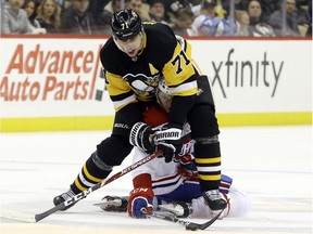 Penguins centre Evgeni Malkin smothers Canadiens' center Matthew Peca while chasing the puck during the third period at PPG Paints Arena Tuesday night.