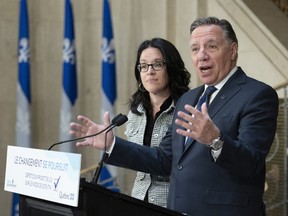 Premier François Legault, with Sonia LeBel, the minister responsible for electoral reform, responds to reporters questions at the National Assembly.