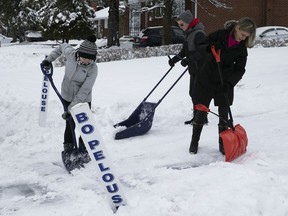 Elspeth Stilton and her children shovel a neighbour's driveway in Pointe-Claire on Jan. 1, 2020.