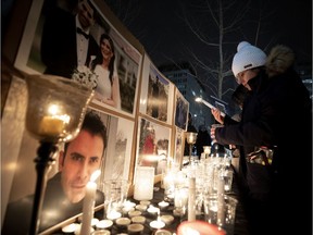 A woman lights a candle on a tribute table featuring pictures of the Montreal victims of Wednesday's plane crash in Iran.