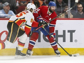 Montreal Canadiens'  Nate Thompson looks to pass the puck under pressure from Calgary Flames' Noah Hanifin during third period in Montreal on Jan. 13, 2020.