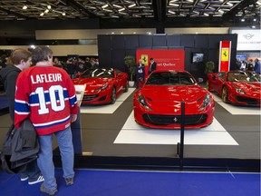 People look over vehicles by Ferrari at the Montreal International Auto Show on Saturday, Jan. 18, 2020.
