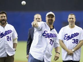 Former Montreal Expo Larry Walker throws a pitch as Darrin Fletcher, left, and Denis Boucher watch while taking part in a pre-game ceremony to honour the 1994 team before a pre-season exhibition game between the Toronto Blue Jays and the New York Mets at the Olympic Stadium in Montreal on March 29, 2014.