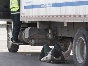 Contrôle routier investigators inspect a truck as Montreal police investigate the scene where a pedestrian was hit by a delivery truck on Côte-Vertu Blvd. near Beaulac St. in St-Laurent on Friday.