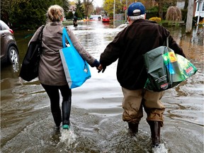 A father and daughter make their way along des Maçons St. in Pierrefonds after rescuing prized family possessions from their home in May 2017.
