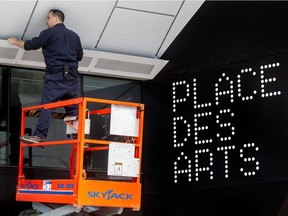 Electrician Robin Lussieris fixes some of the lights at an entrance to Place des Arts in preparation for the jazz fest in Montreal on June 26, 2015.