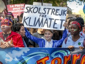 Greta Thunberg raises her climate strike sign while sharing the front row of climate march with native youths in Montreal on Friday, Sept. 27, 2019.